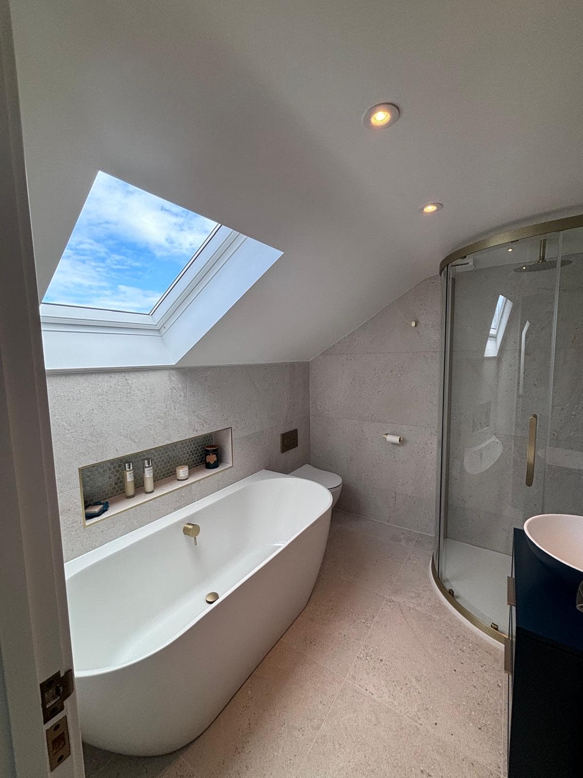 Loft conversion en-suite with a Velux rooflight, freestanding bath and brass fittings, completed by FR Carpentry